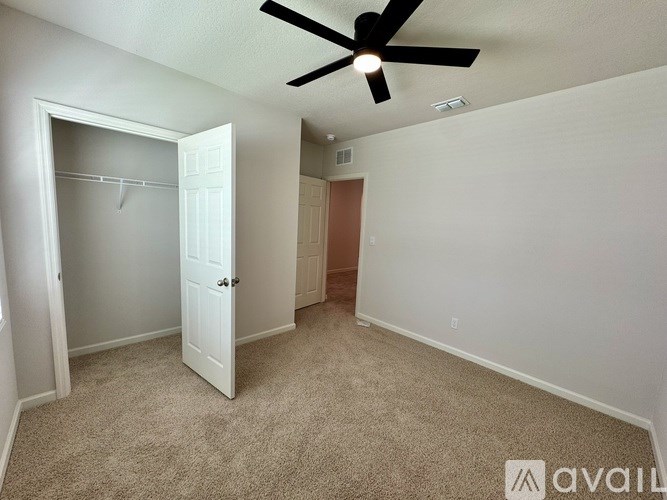 A room with a ceiling fan and carpeted floor.