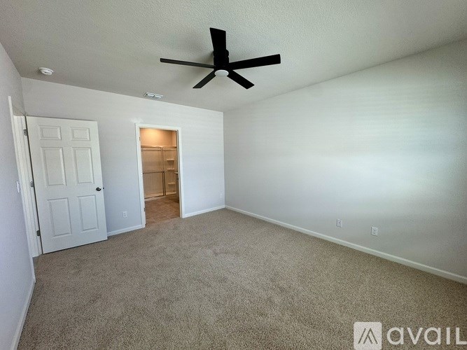 A room with a ceiling fan and carpeted floor.