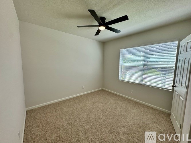A room with a ceiling fan and carpeted floor.