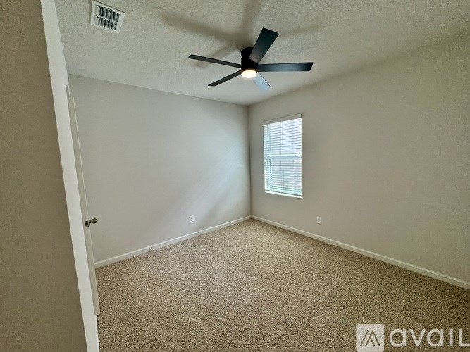A room with a ceiling fan and a window with blinds.