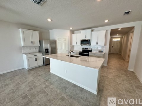A kitchen with white cabinets and a marble island.