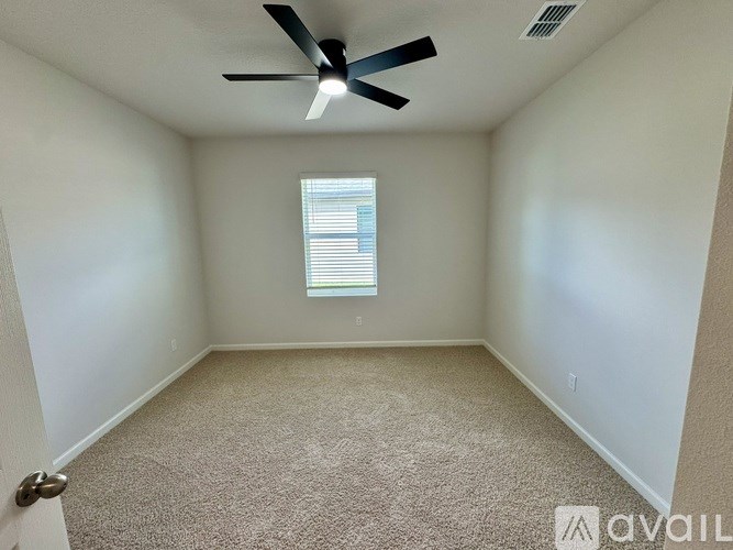 A room with a carpet floor, a ceiling fan, and a window with blinds.