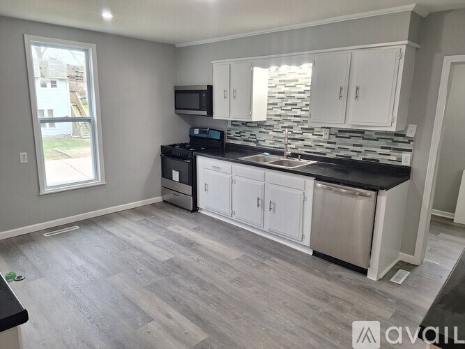 A kitchen with a black countertop and white cabinets.