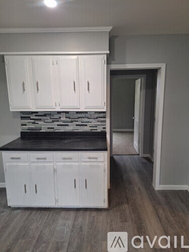 A kitchen with white cabinets and a black countertop.