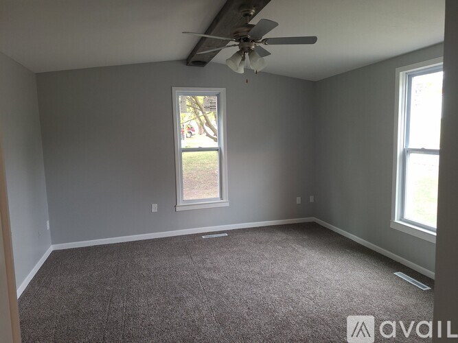 A room with a ceiling fan and carpeted floor.