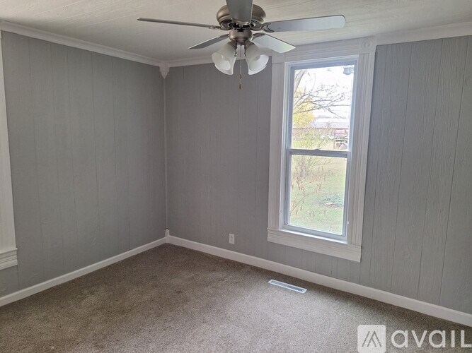 A room with a ceiling fan and a window.
