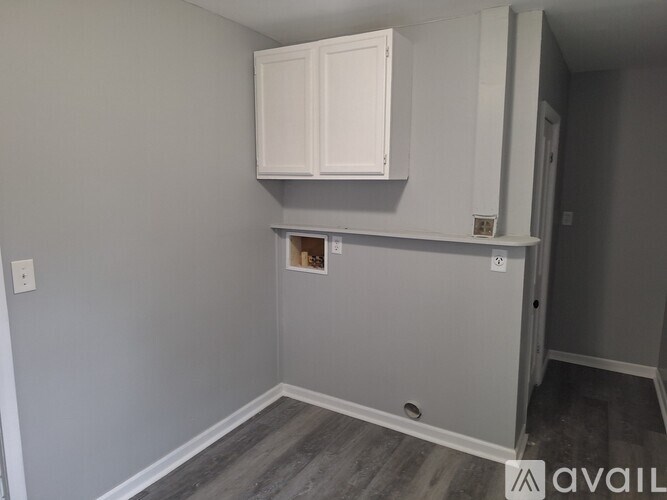 A room with a white cabinet and a grey wall.