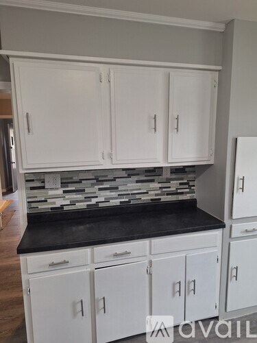 A kitchen with white cabinets and a black countertop.