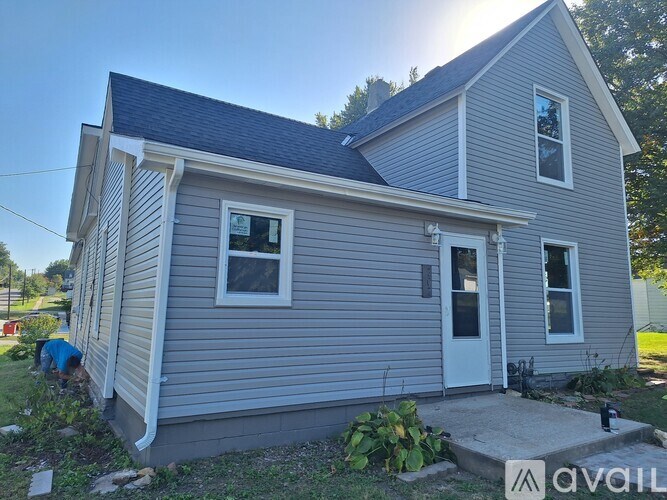 A house with a grey siding and a white door is shown.