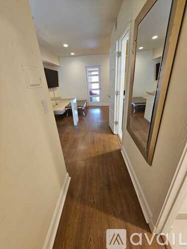 A hallway with wood floors and white walls.