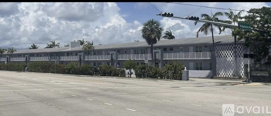 A street view of a building with a fence and palm trees.