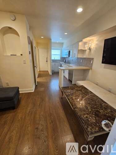 A kitchen with a marble bench top and wooden floors.