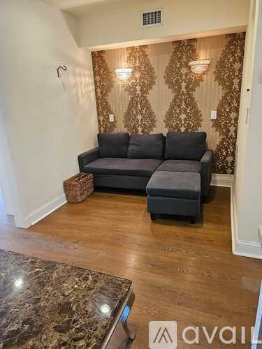 A grey couch with a pillow and a basket on the floor.