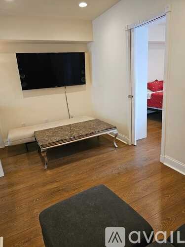 A room with a flat screen TV mounted on the wall and a red couch in the background.