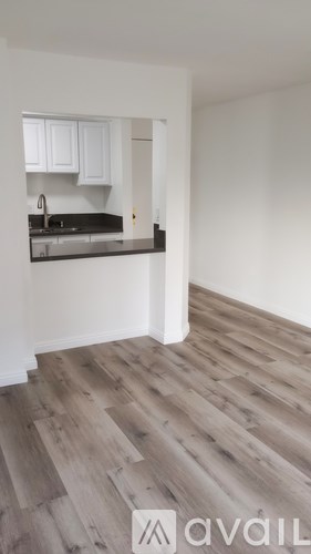 A kitchen with white cabinets and a wooden floor.