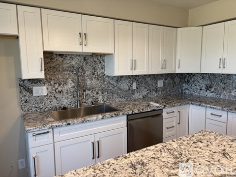 A kitchen with granite countertops and white cabinets.