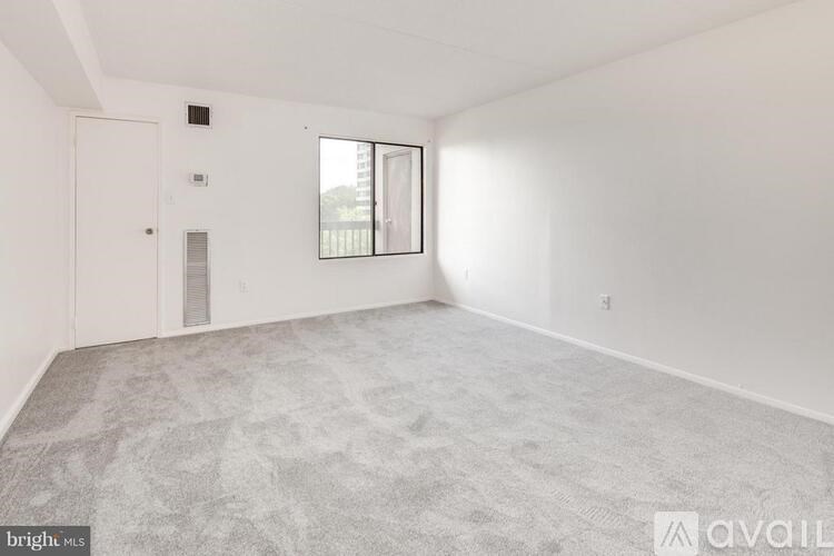A spacious room with a carpeted floor and a window.