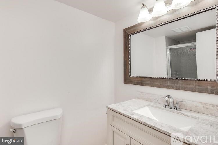 A bathroom with a white toilet, a marble sink, and a mirror.