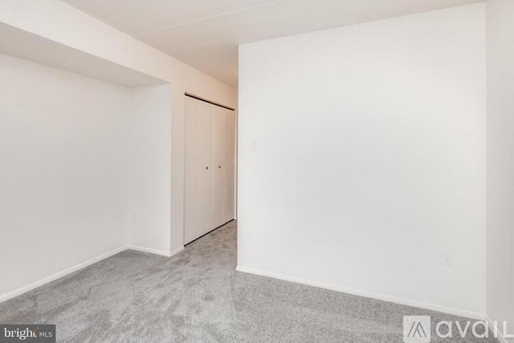A room with a carpeted floor and a white wall with a door.