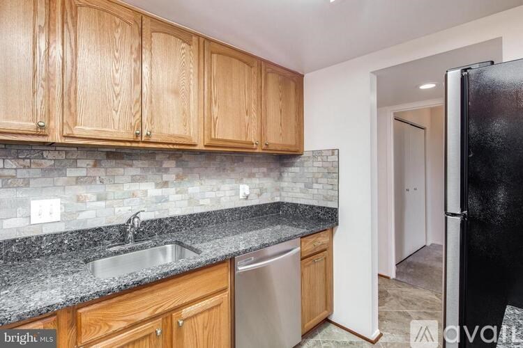 A kitchen with wooden cabinets and a black refrigerator.
