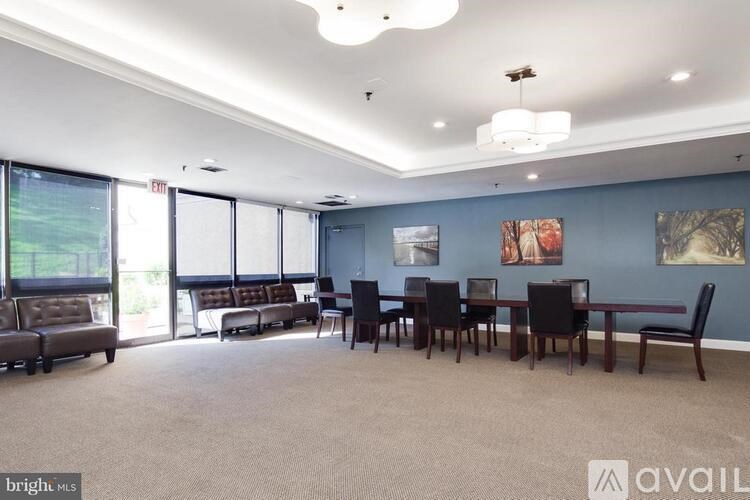 A spacious room with a long table and chairs, a sofa, and a large window with a view of greenery outside.