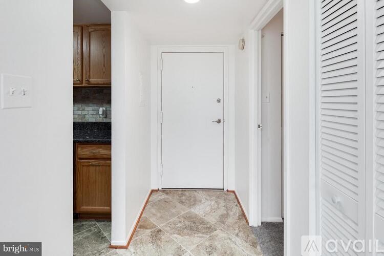 A hallway with a white door and a tiled floor.