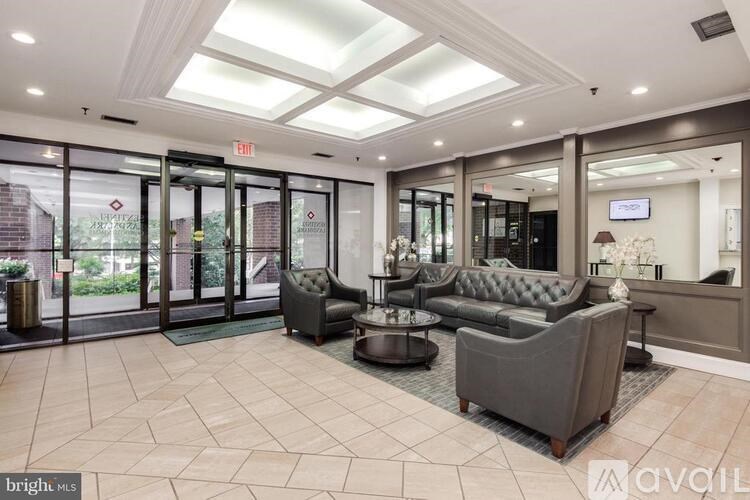 A bright and spacious waiting room with grey couches and a reception desk.