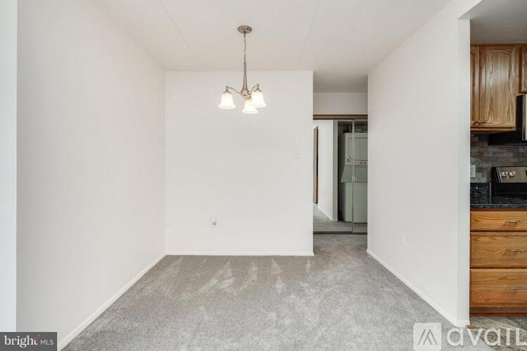 A room with a grey floor and a white wall with a chandelier hanging from the ceiling.