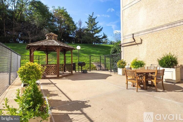 A gazebo is surrounded by a fence and a table set for four.