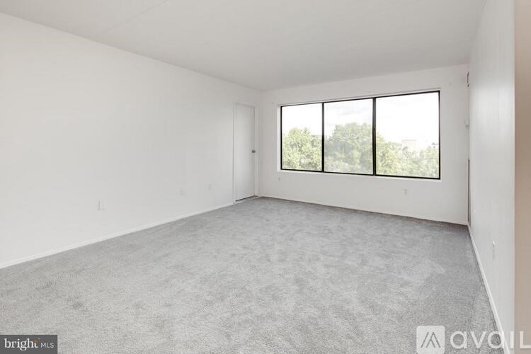 A spacious room with a carpeted floor and a large window.