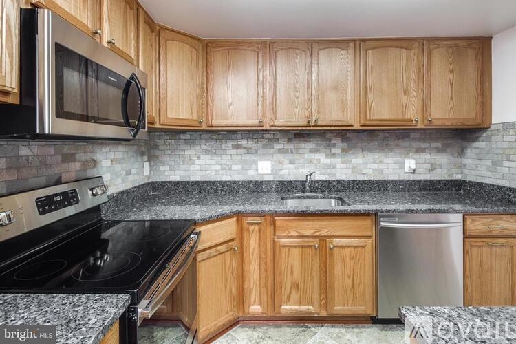 A kitchen with wooden cabinets and a black countertop.