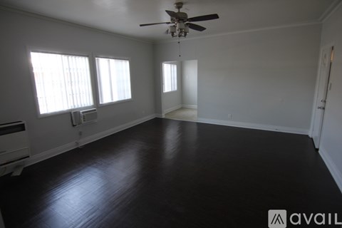 A spacious room with a ceiling fan and three windows.