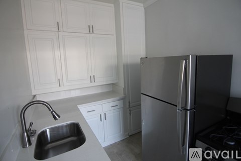 A kitchen with white cabinets and a stainless steel refrigerator.