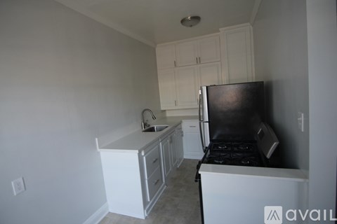 A kitchen with white cabinets and a black fridge.