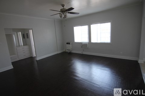 A room with a ceiling fan and two windows.