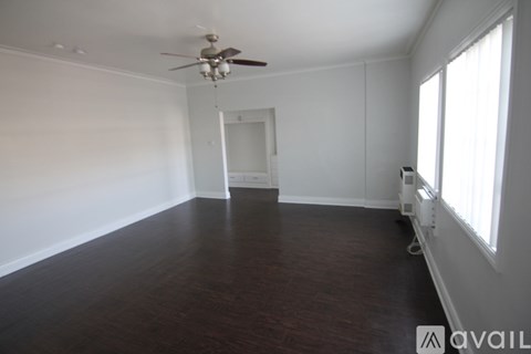 A spacious room with a ceiling fan and wooden flooring.