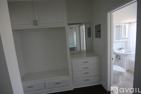 A bathroom with a toilet, sink, and cabinets.