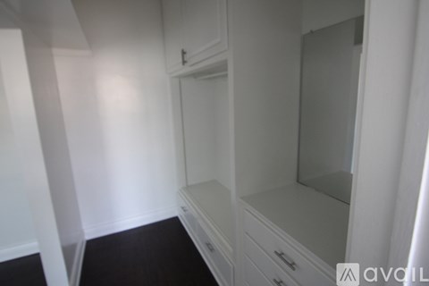 A white cabinet with a mirror and drawers in a room.