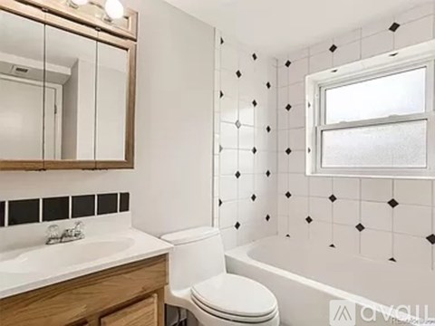 A white toilet sits next to a sink in a bathroom with black and white tiles.