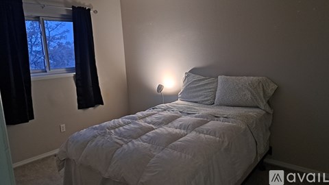A bedroom with a bed, pillows, and a window with curtains.