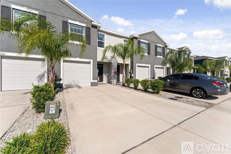 A modern house with a grey facade and a black car parked in the driveway.
