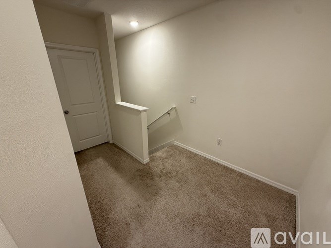 A small, empty room with a carpeted floor and a door.