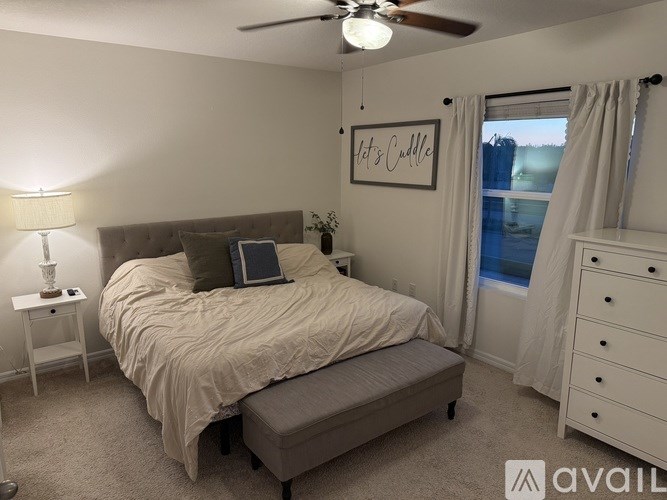 A bedroom with a bed, nightstand, and window.