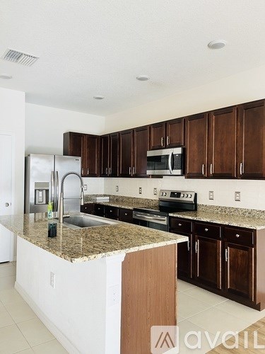 A kitchen with brown cabinets and granite countertops.
