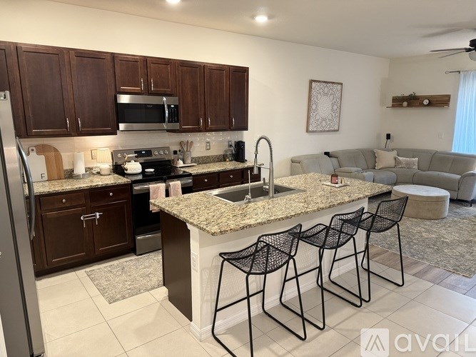 A lighthouse stands between two palm trees under a blue sky.