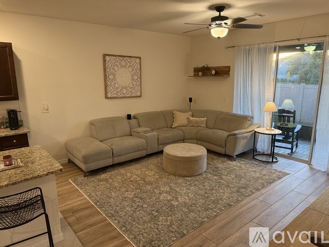 A living room with a grey sofa set and a rug.