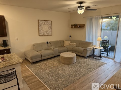 A living room with a grey sofa set and a rug.