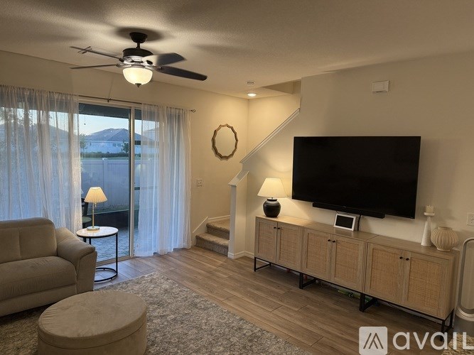 A living room with a television, a couch, and a fan.