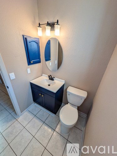 A bathroom with a toilet, sink, and mirror.