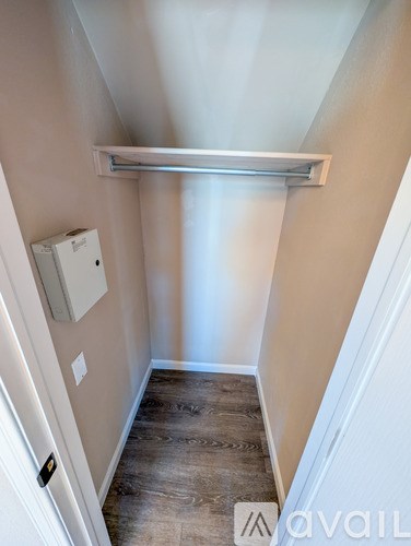 A narrow hallway with a white door and a white wall-mounted object.